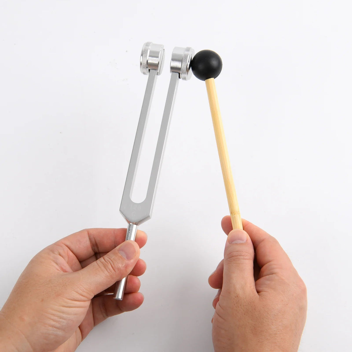 Real wooden mallet and weighted tuning fork held by the stem