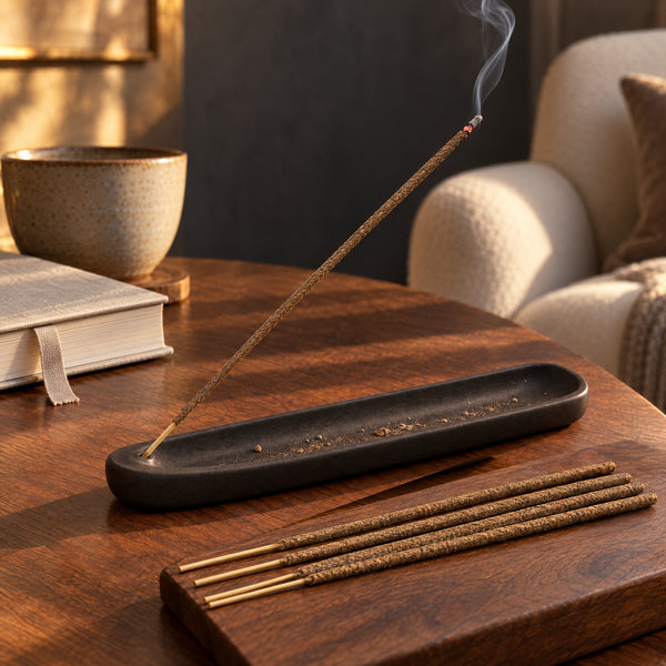 Tan-brown Frankincense and Myrrh incense smoldering in a charcoal ceramic tray on walnut.