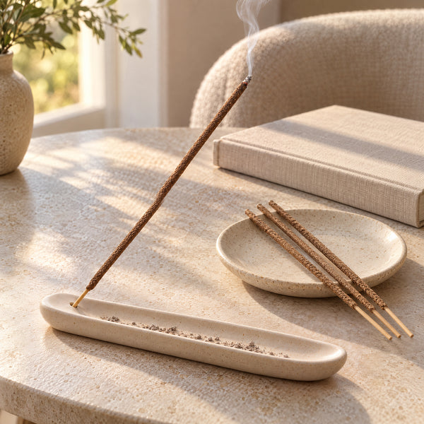 Brown Vanilla incense in a pale ceramic holder beside a blank closed book.